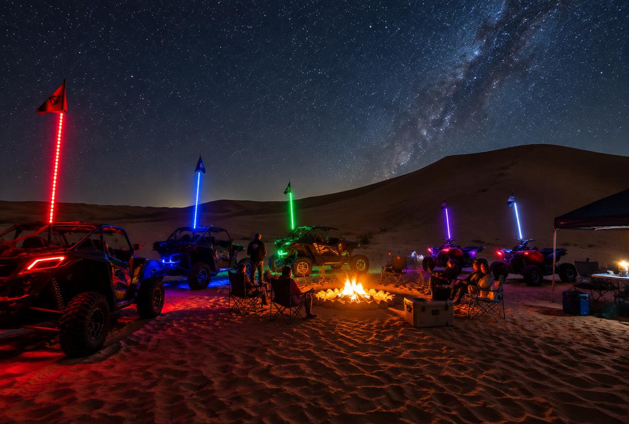 Night dune camp with whip lights and a campfire under the stars